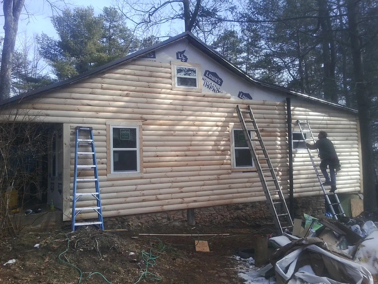 Ladders set against fresh log siding during an exterior remodel in South Greenfield