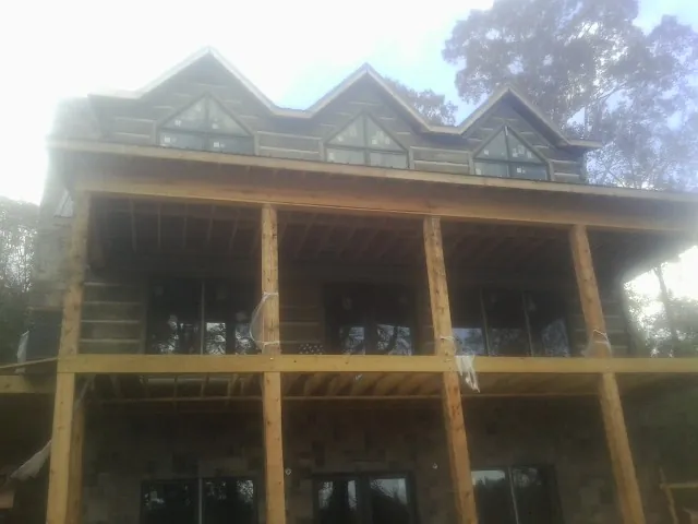 Dormers and porch framing on a large log home under construction — Roof Coating work by our crew in South Greenfield
