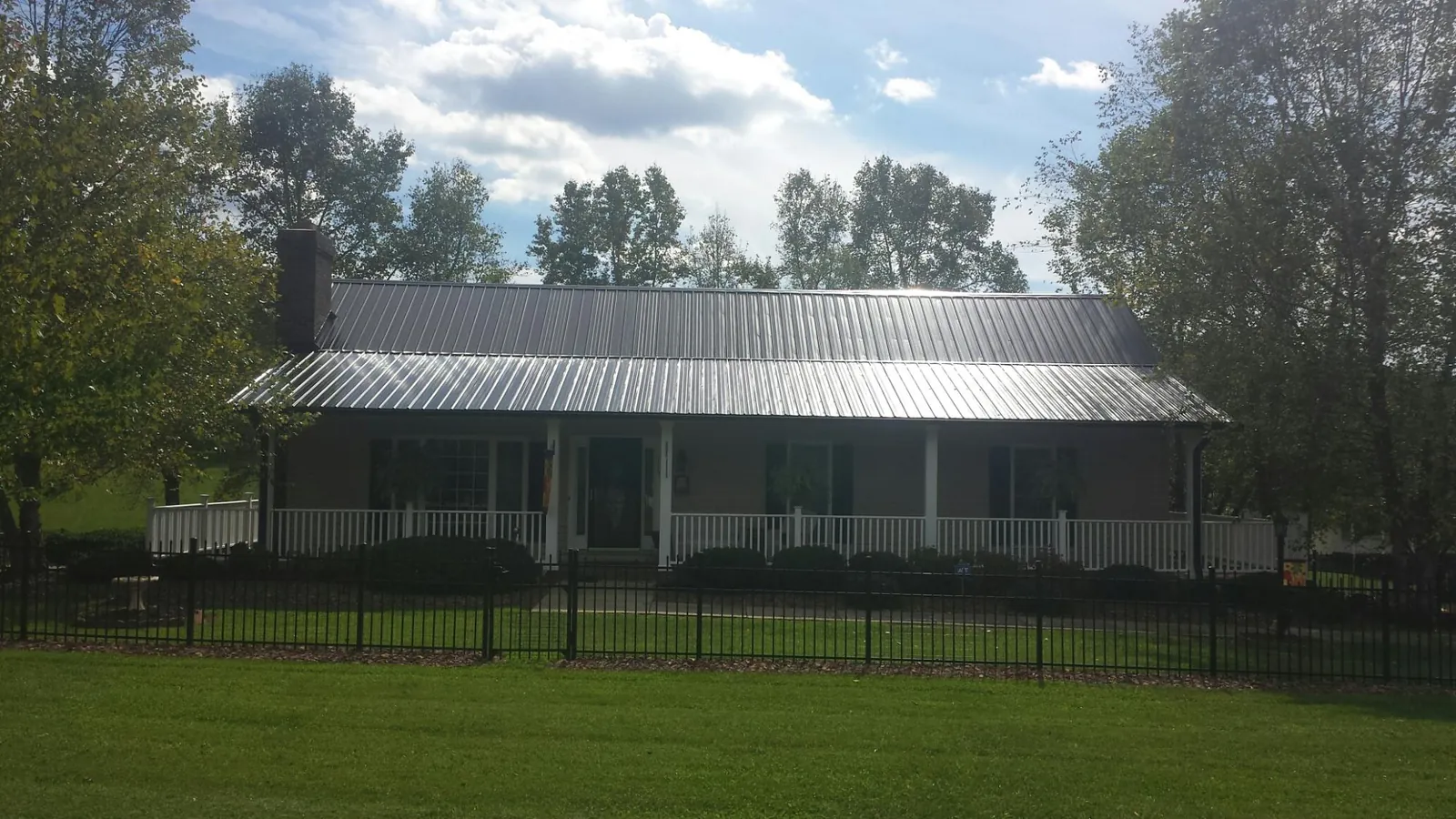 Gray metal roof on a brick ranch with a full width front porch — Gutter Guard Installation work by our crew in South Greenfield