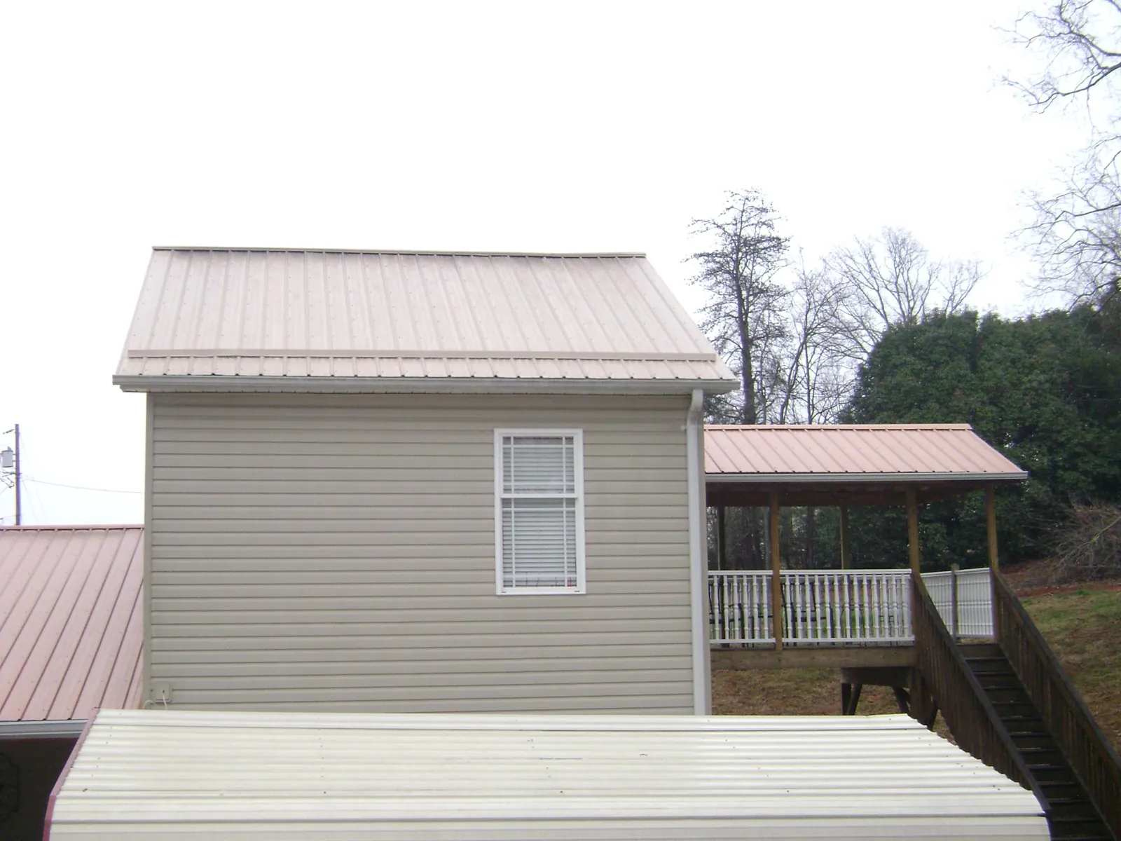 Tan metal roofs on a two story addition and attached porch, from a Roof Replacement job in South Greenfield