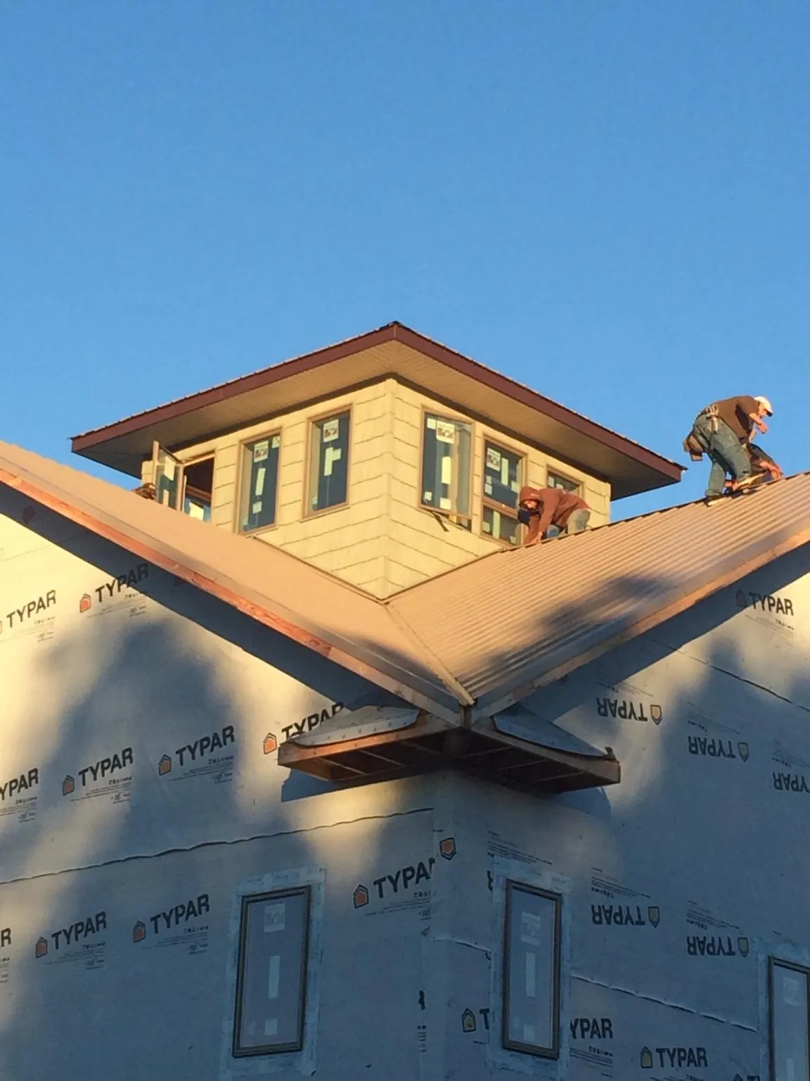 Roofers working around a rooftop cupola on a new metal roof at sunset — Roof Waterproofing in South Greenfield by Roofing Brothers